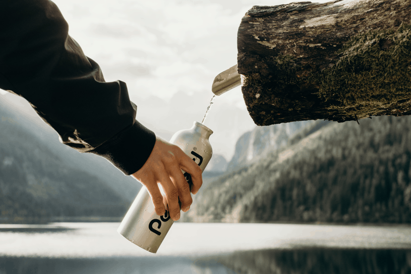 person holding bottle near nozzle; Photo by Kate Joie from Unsplash